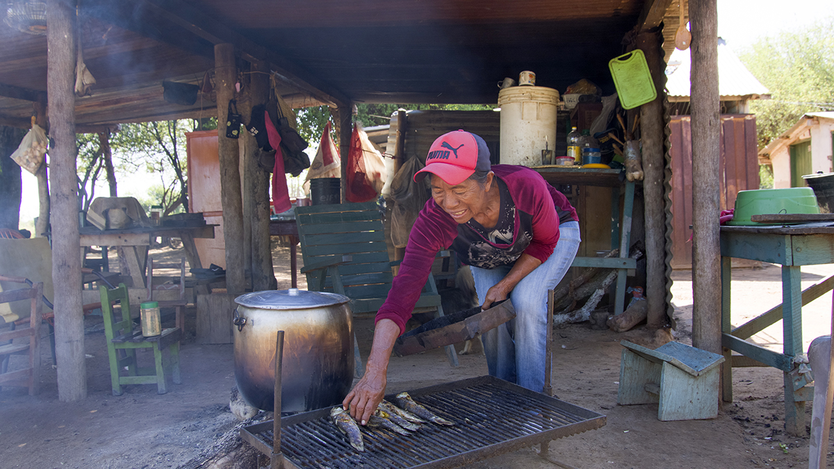 Mujer indígena cocinando su pesca. Solidaridad